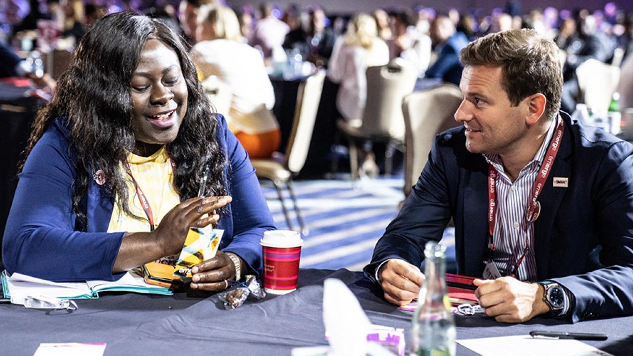 Two people talking at a table at the conference