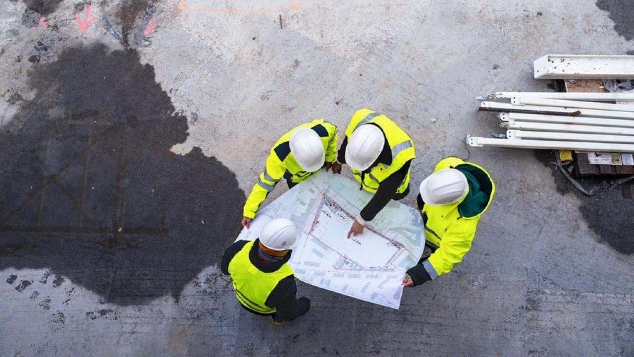 Aerial view of four construction workers overlooking a blueprint.
