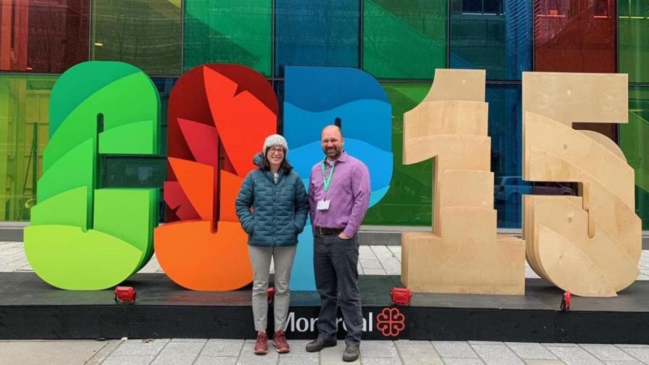 Two people in front of a COP 15 sign