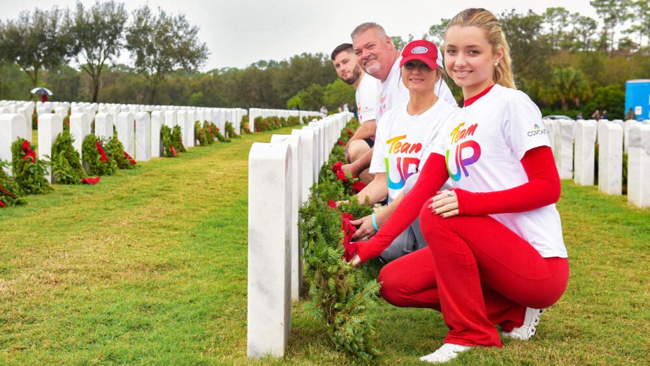 group posing with wreaths at headstones