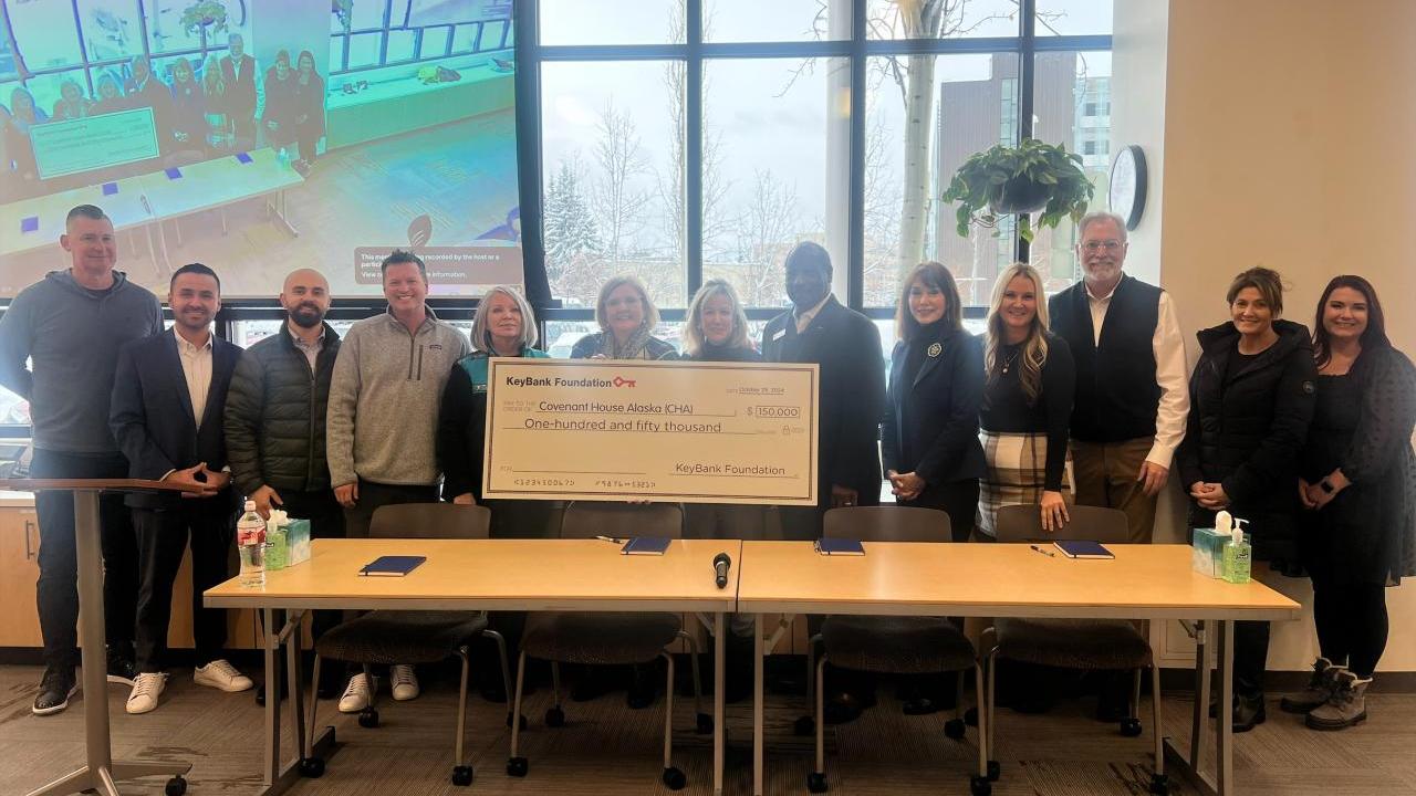 People standing behind a desk, holding an oversized check