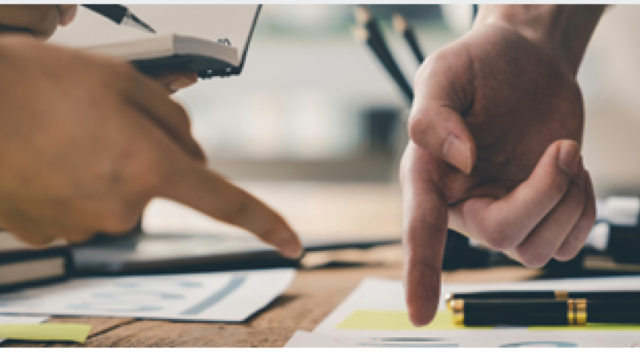 Two people pointing to a piece of paper.