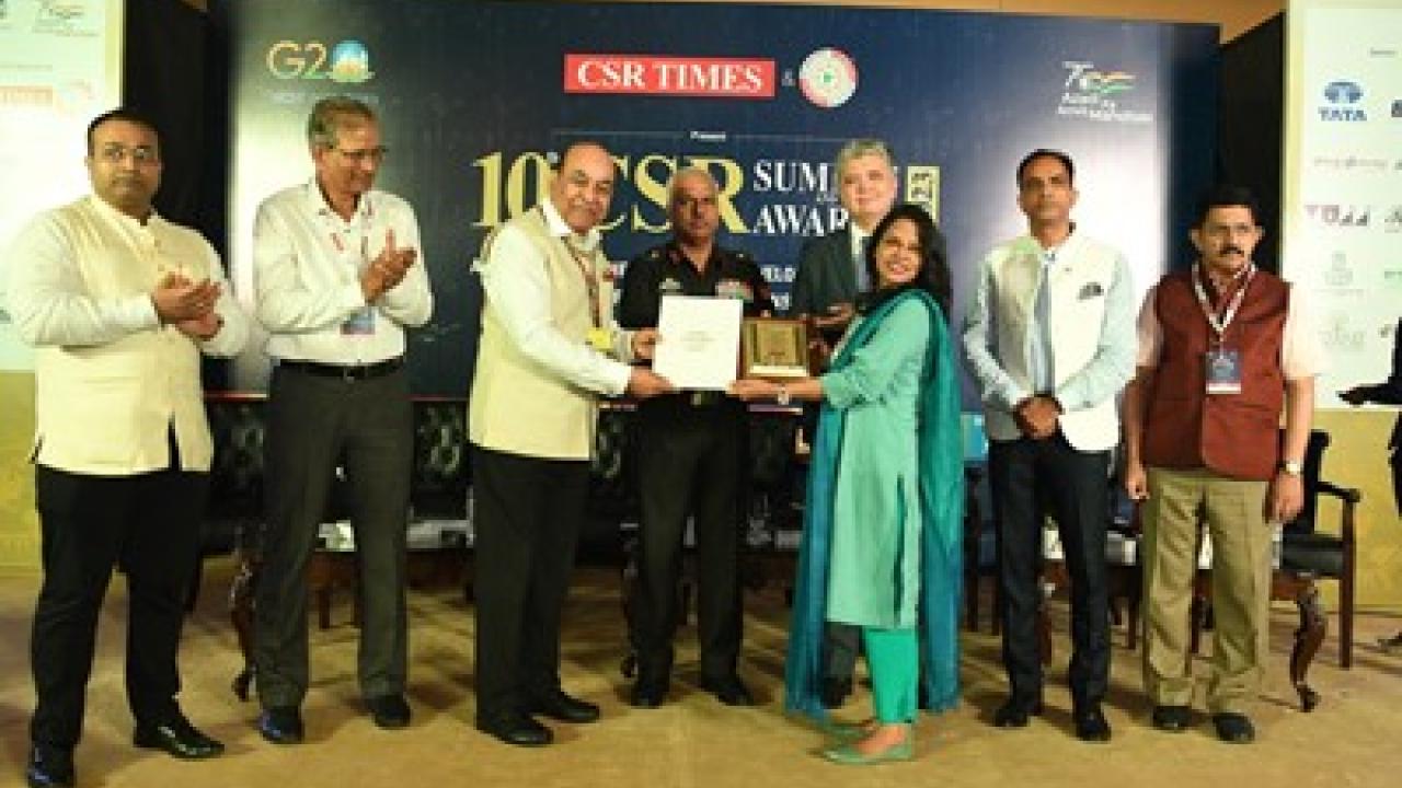 A row of people on a stage. Three holding an award.