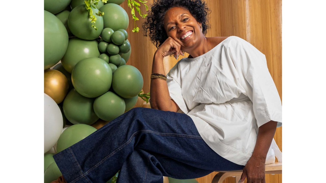 Person sitting on a chair next to green balloons