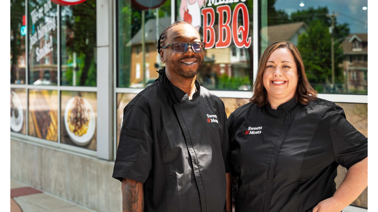 Two people standing in front of a BBQ establishment