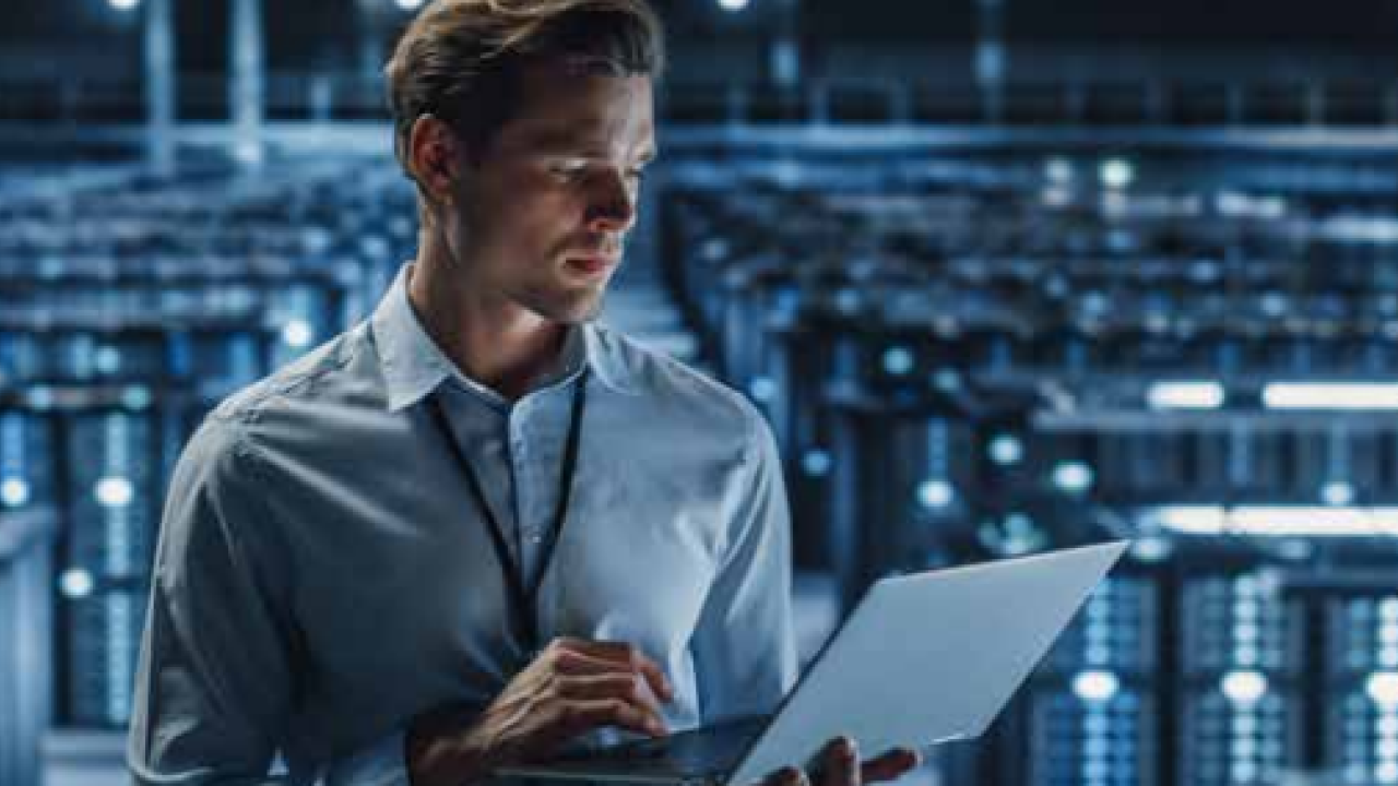 A man holding a laptop in a server room