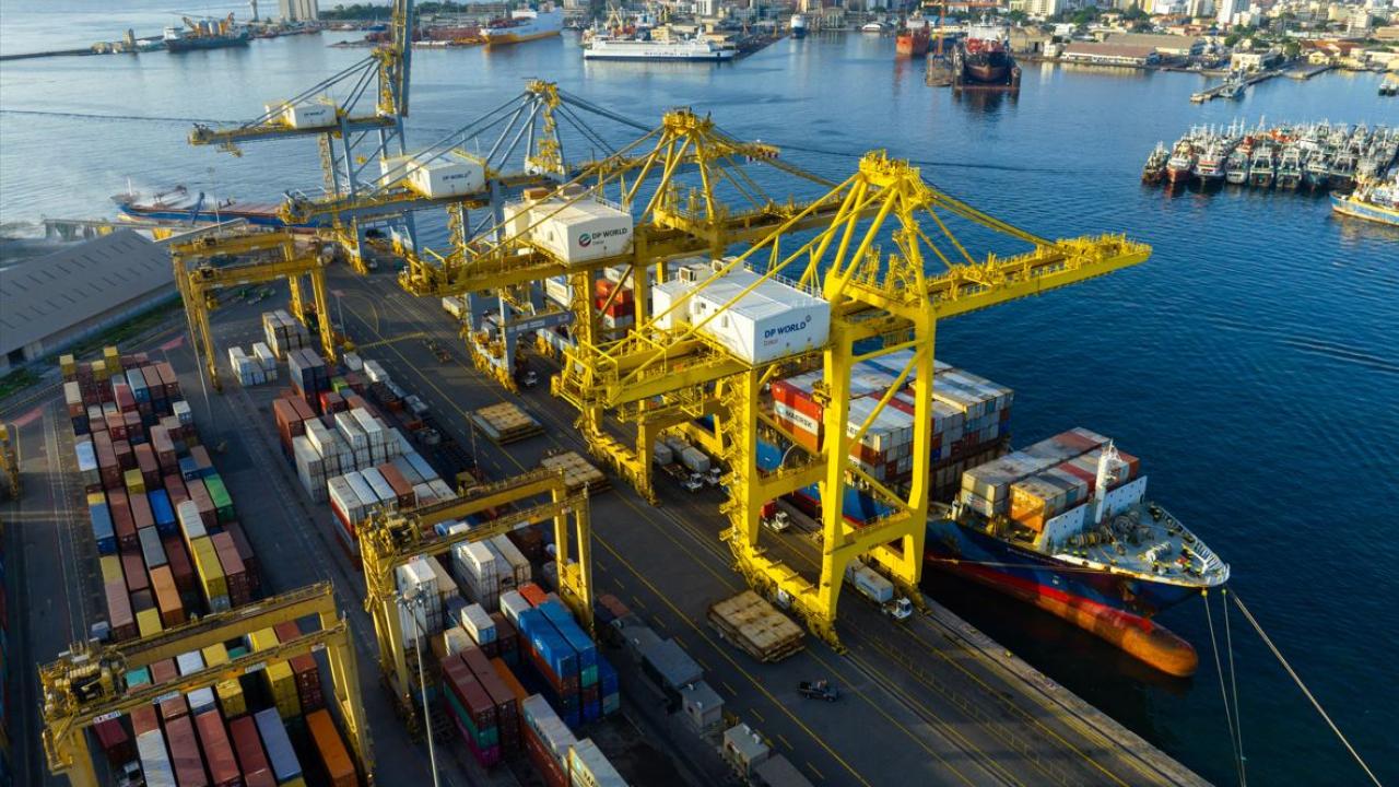 Aerial view of DP World’s container terminal at the Port of Dakar, Senegal, showing yellow gantry cranes loading cargo ships and colorful containers along the quay, with the city skyline in the background.