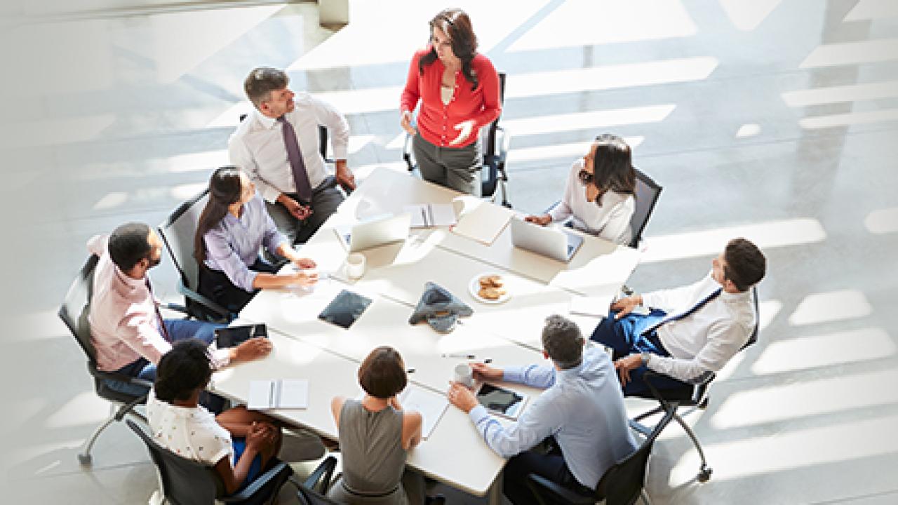 employees sit around a square table in a white room