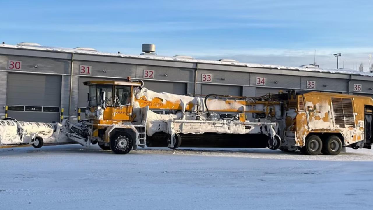 A large de-icing machine outside covered in snow
