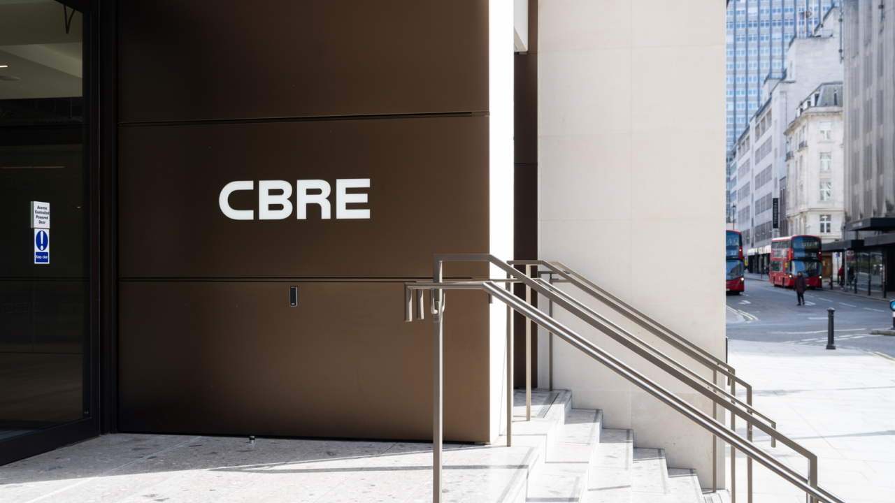 Exterior sign on a building "CBRE" nest to a short staircase.