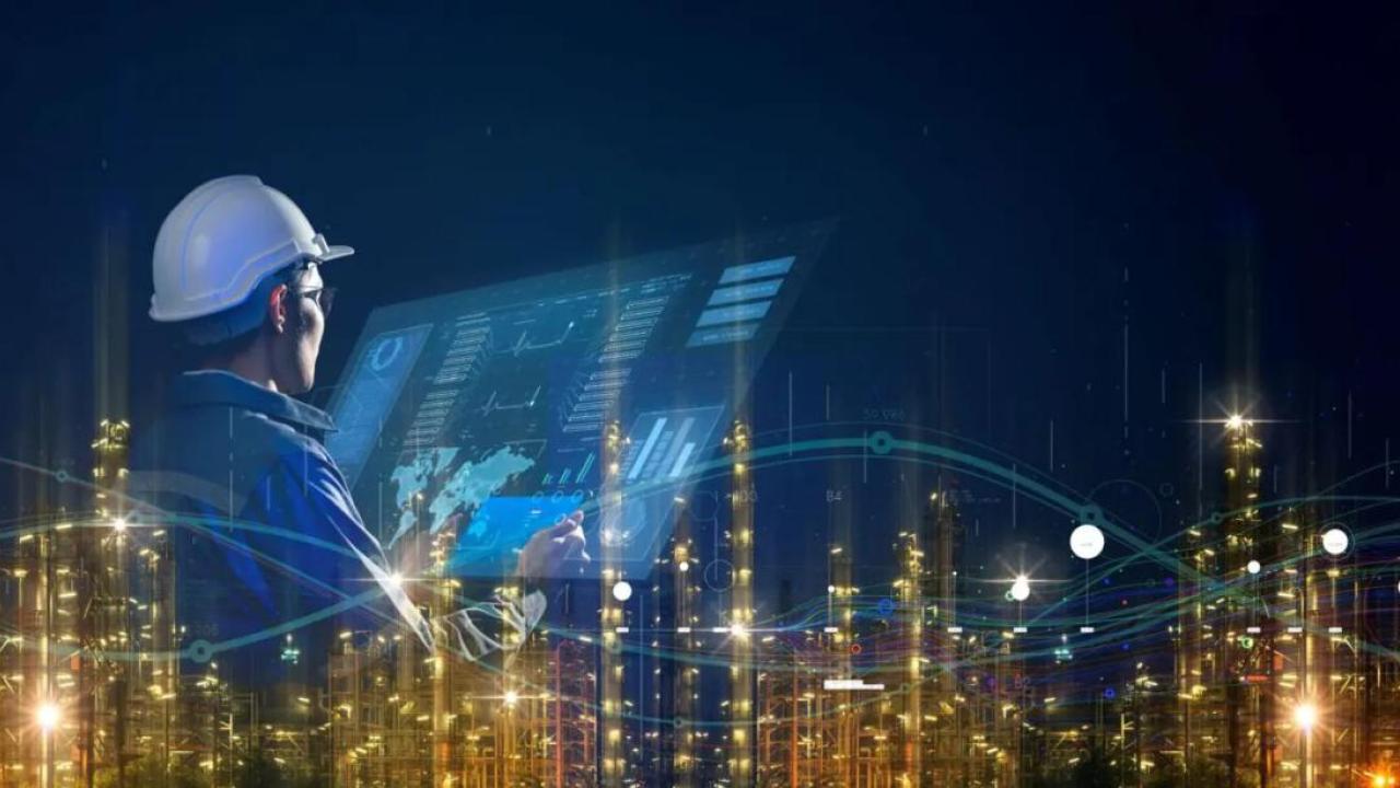 Digital image of a city sky line, an image of a person in a hard hat looking at a large digital screen overlays it.