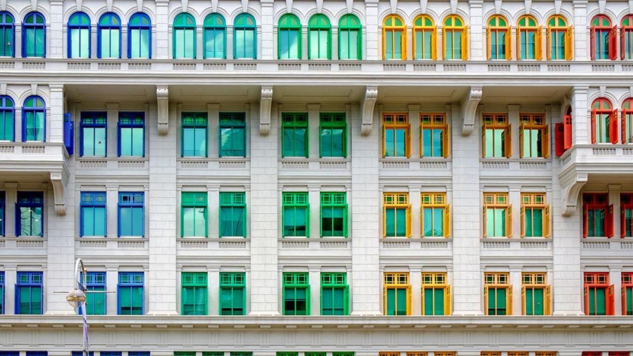 exterior view of rows of rainbow colored window frames on a white building