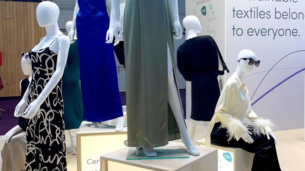 Manequins in different dresses. A display "Sustainable textiles belong to everyone." behind them.