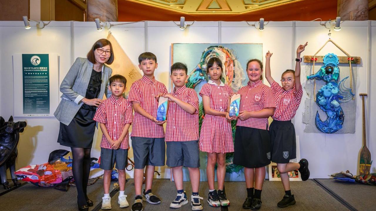 A group of children and an adult posed in front of an exhibit with sea creatures.