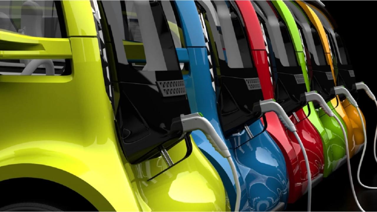 close row of different colored electric vehicles all plugged in