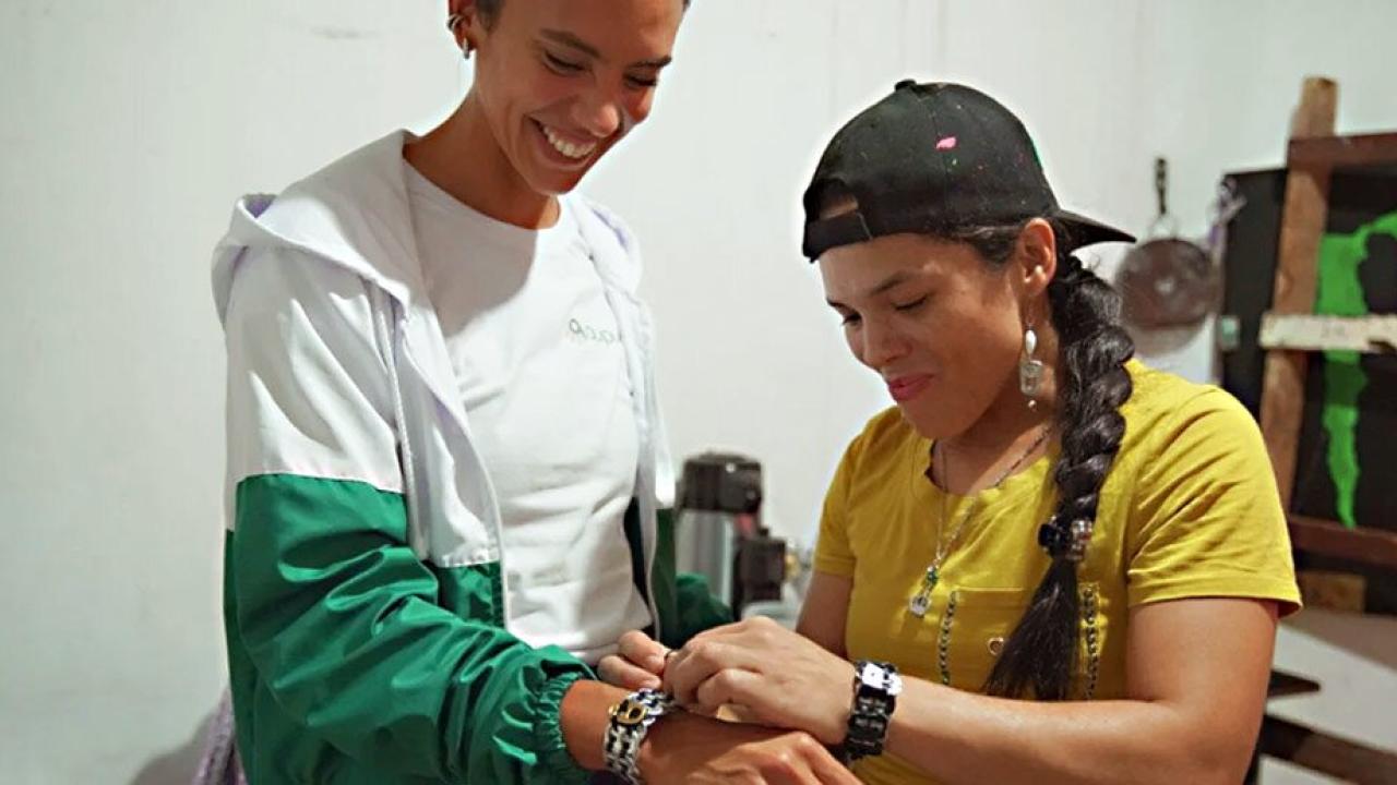 Woman assisting customer in trying on bracelet