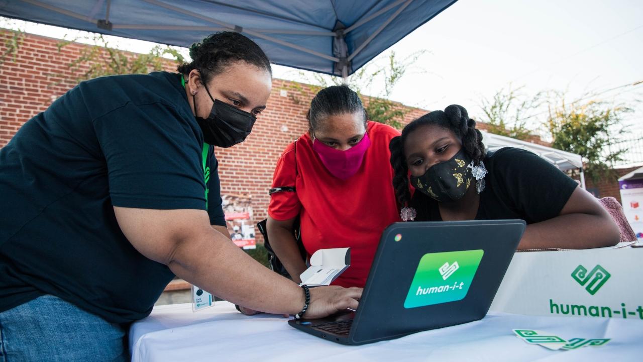 Three people looking at a Human-I-T laptop