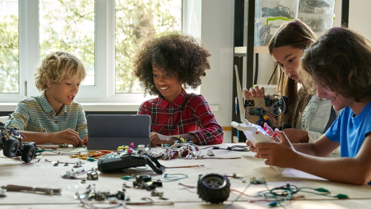 Four children sat around a table using technology 
