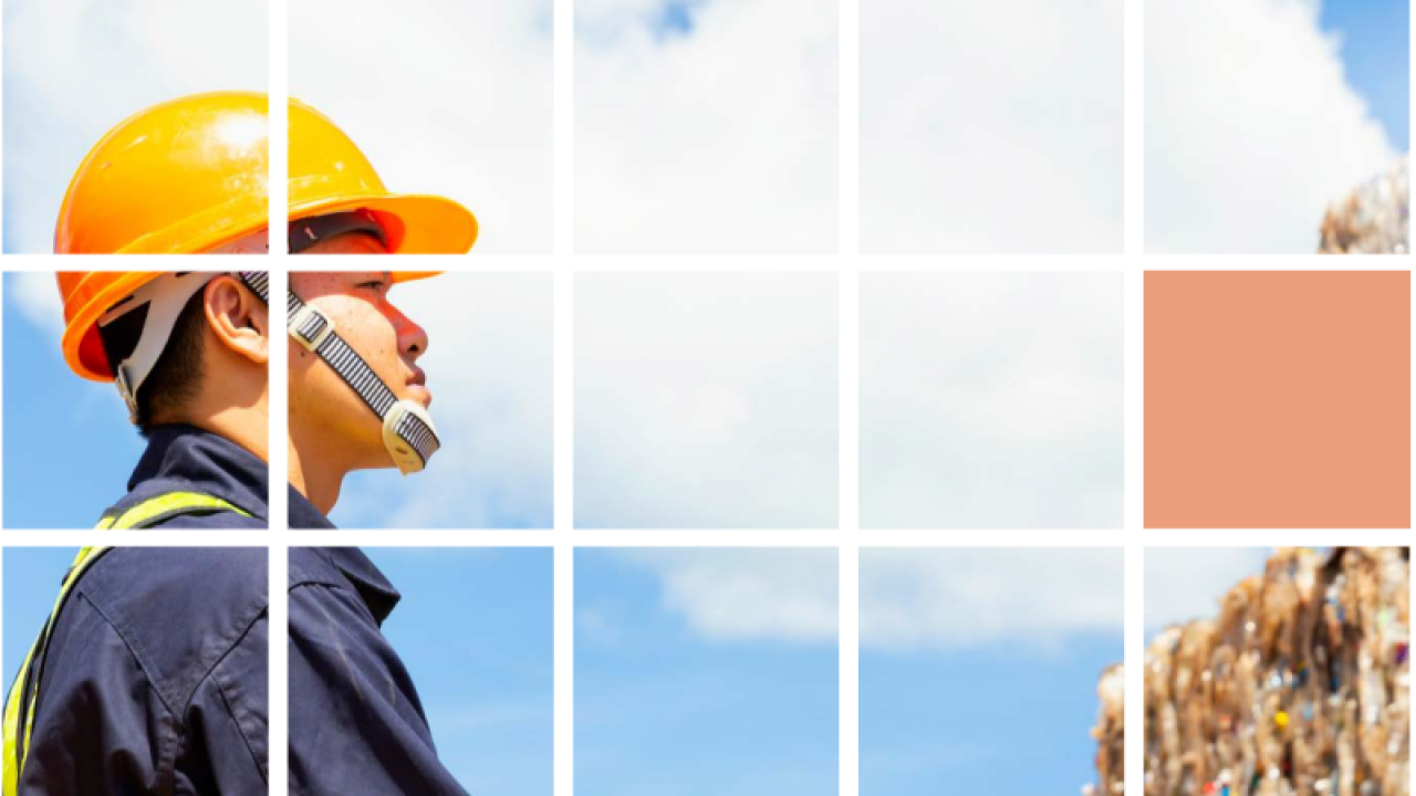 A person wearing a hard hat and protective gloves and vest looking at stacks of material. A white grid overlaid.