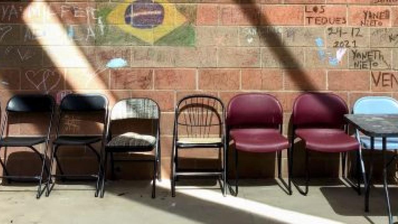 a row of empty chairs against a brick wall 