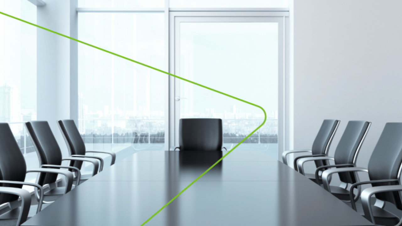 An empty conference room with long table and office chairs around it.