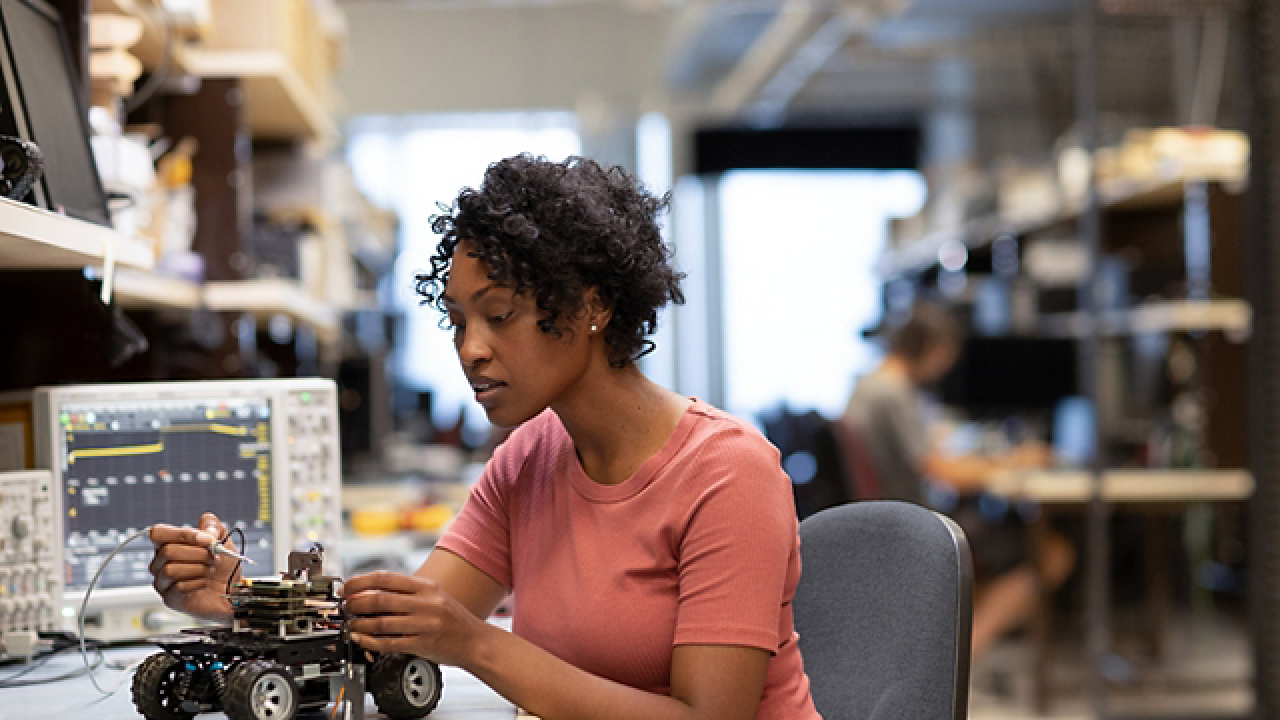 A person working on a small robotic vehicle
