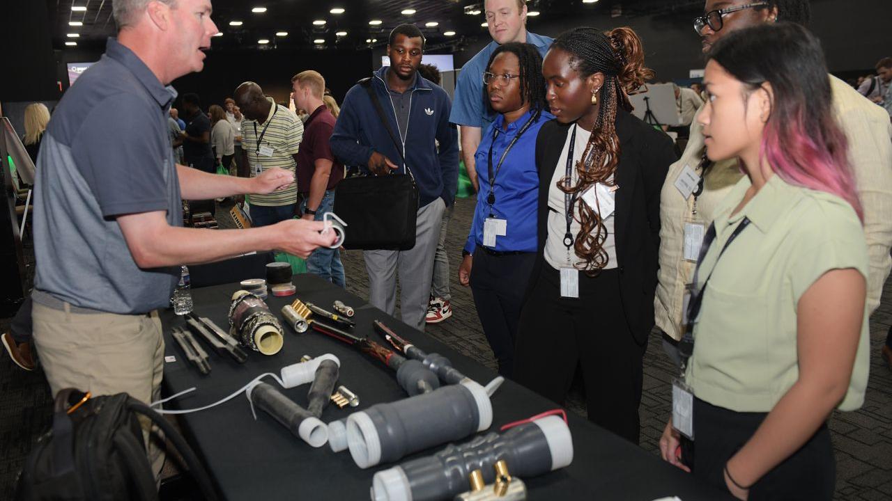 A person standing at a booth showing others parts.
