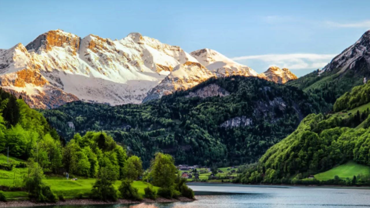 landscape of snow topped mountains down to wooded hills and river