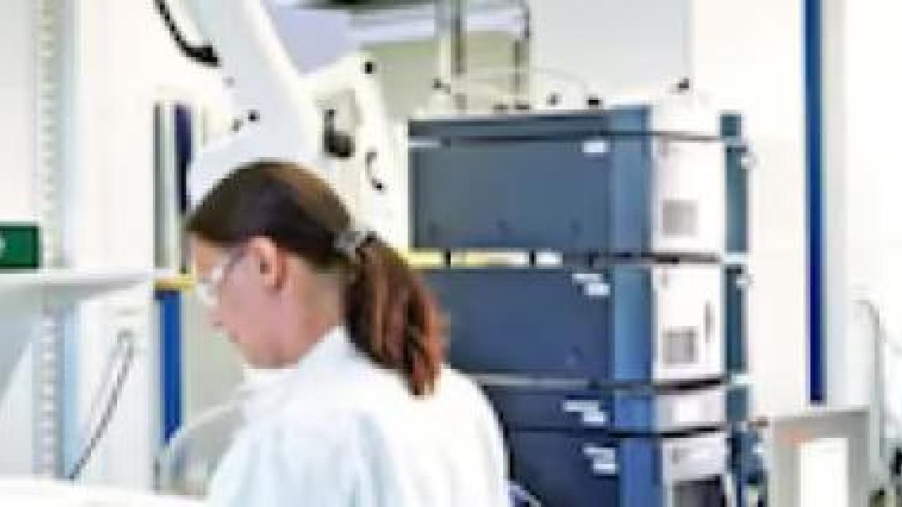Two people in a lab wearing protective gear.