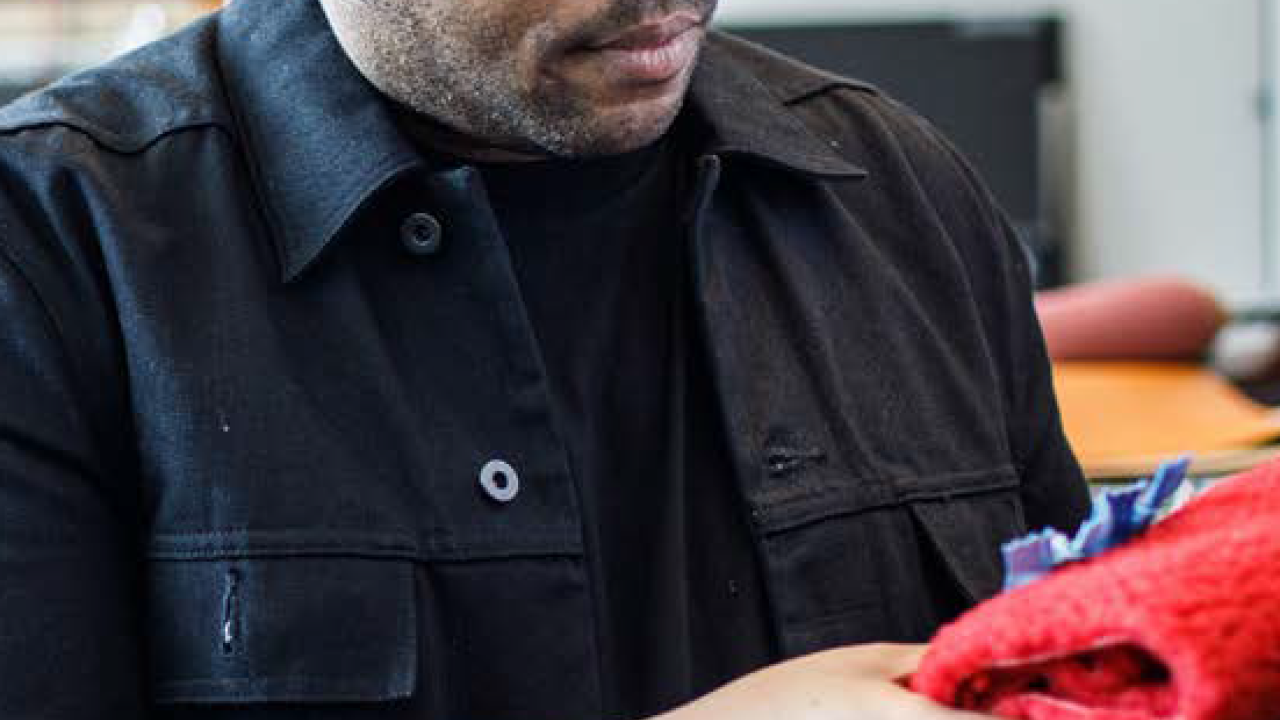 a person holds and looks at a red garment