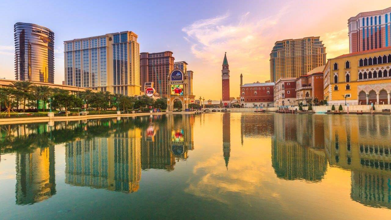 Scenic water view with skyline of tall buildings and sunset in the distance.