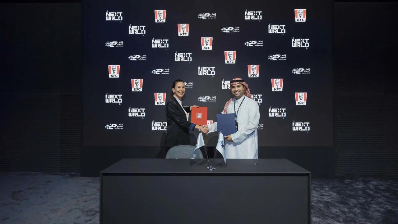 Representatives from SEF and KFC shake hands behind a black desk