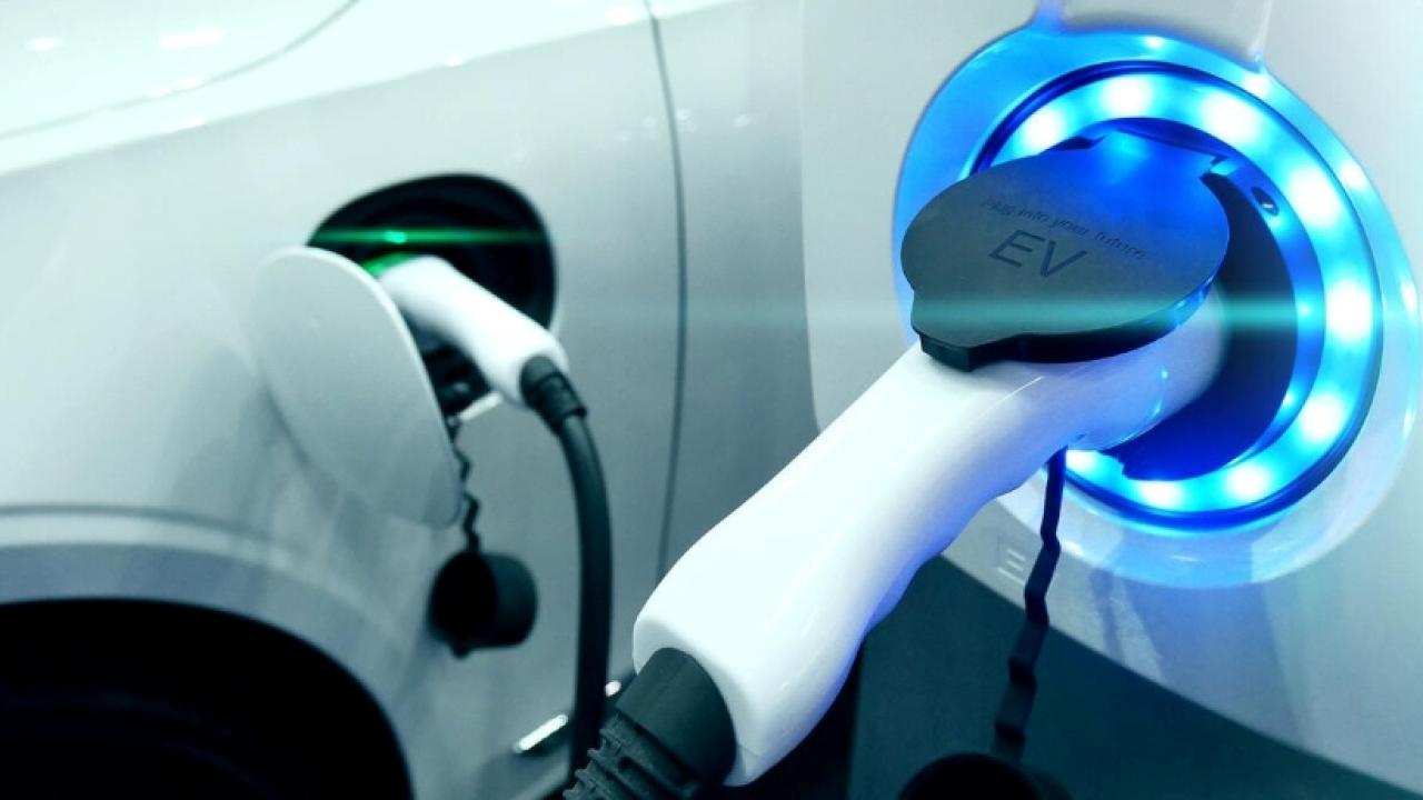 A white electric vehicle, plugged in.