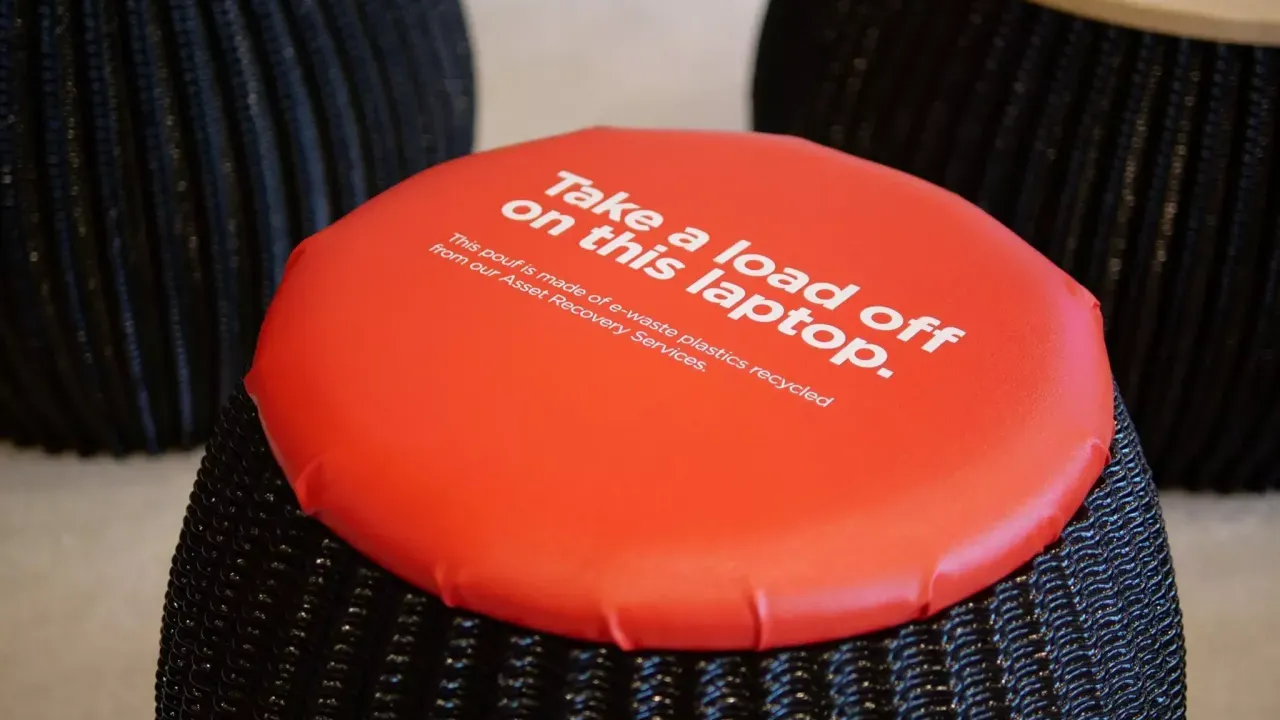 A black stool with Orange cushion "Take a load off on this laptop." printed on top.