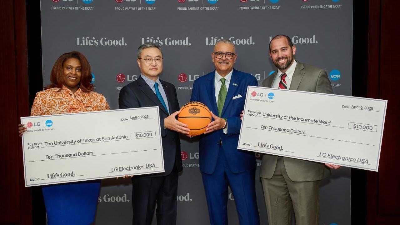 Four people posing with two oversized checks and a basketball