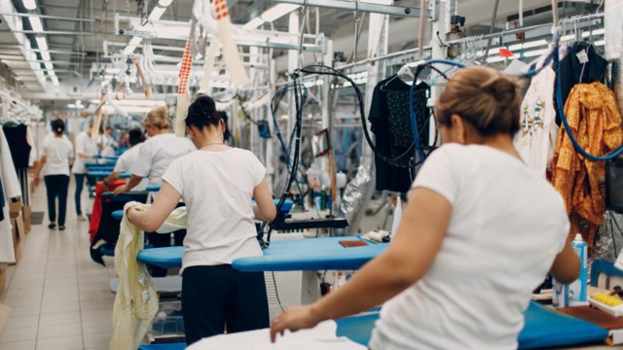 Line of workers standing by irons at garment factory
