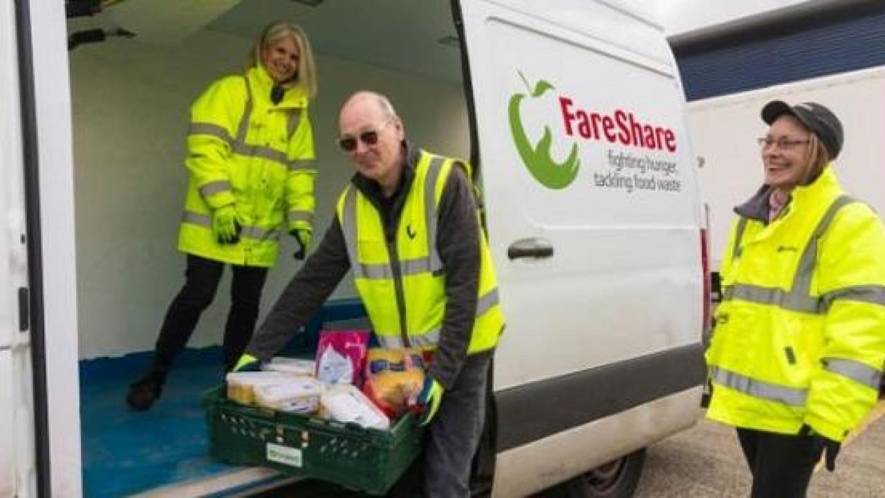People loading crates of food onto a small truck. "FareShare" on the side.