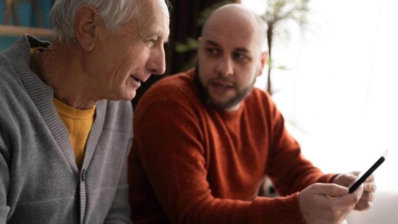 Senior speaking to a younger man about a smartphone
