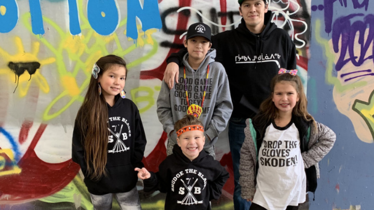 An adult and four children in front of a wall mural