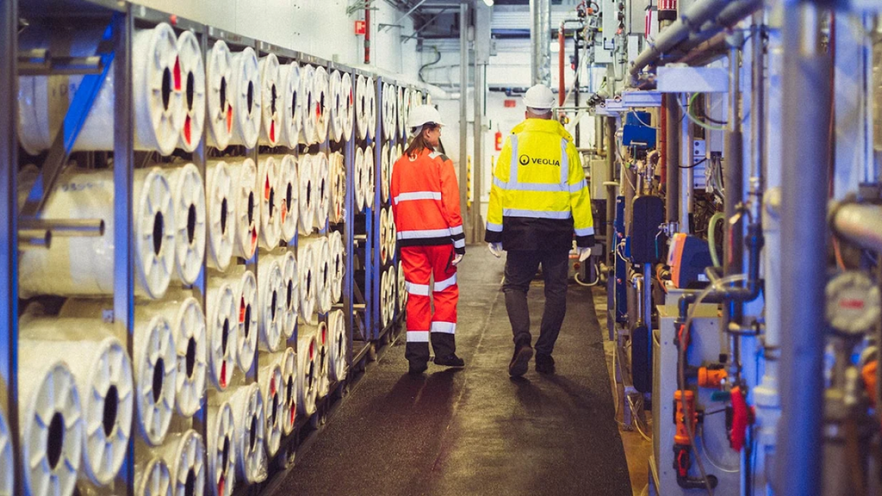 Two people in high-vis gear walking through a plant