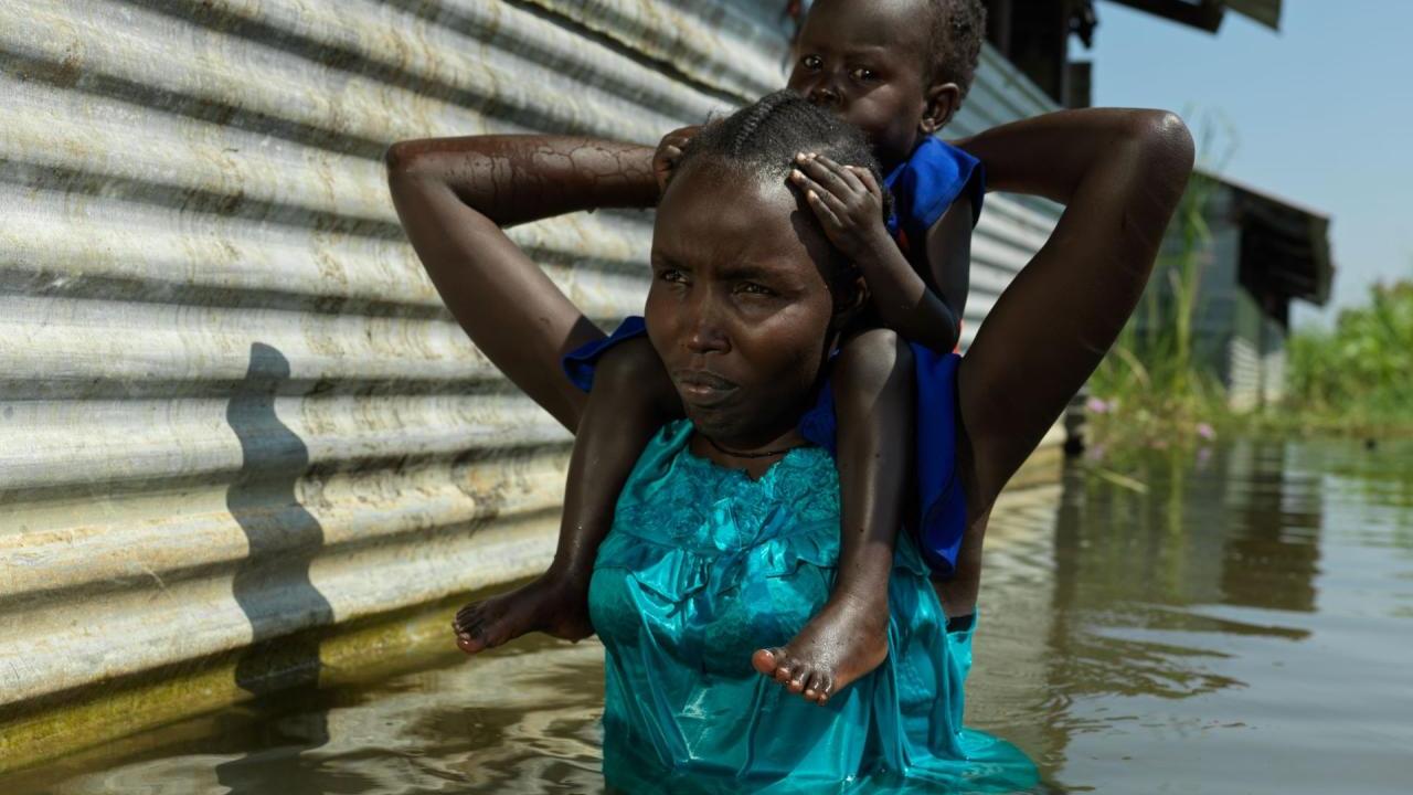 Aweng Thang wades through water with her daughter in Old Fangak.