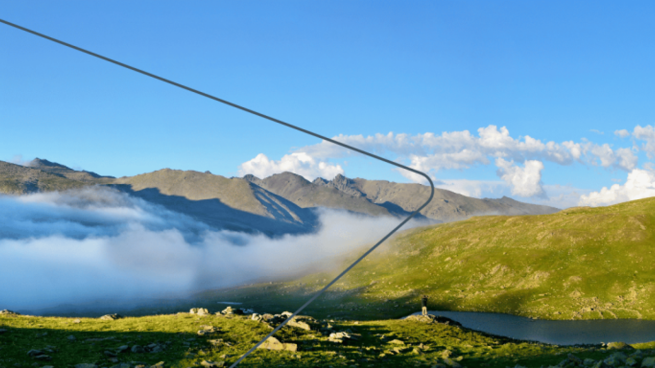 Panoramic view of hills and fog running through the valleys. A blue sky above with very few clouds.