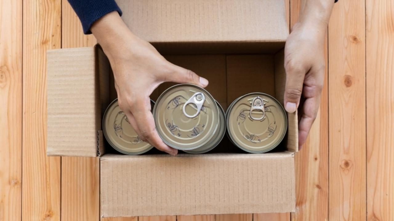 Hands packing canned food into a box