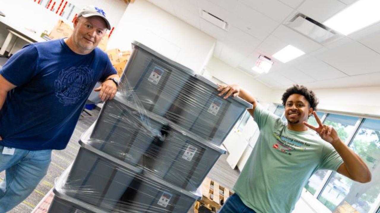 Two volunteers next to large boxes