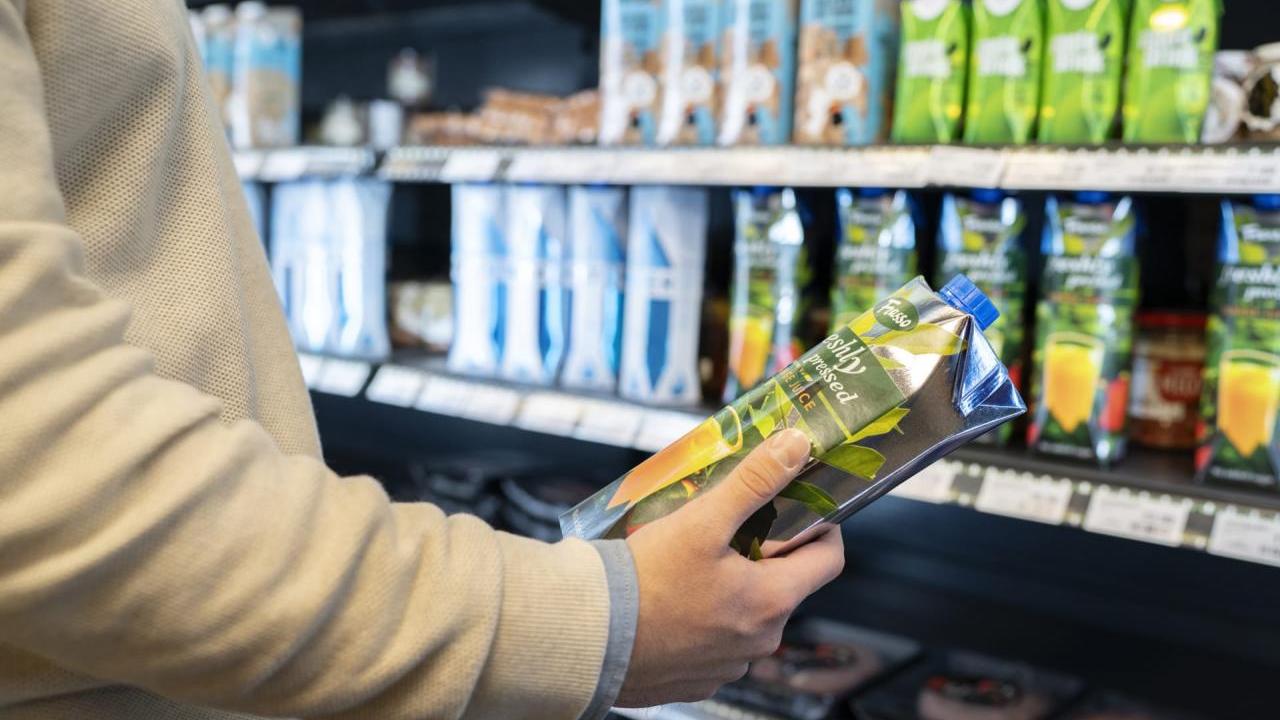A person holding a beverage container in a store.