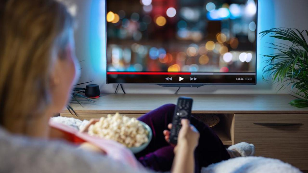person watching tv and eating popcorn