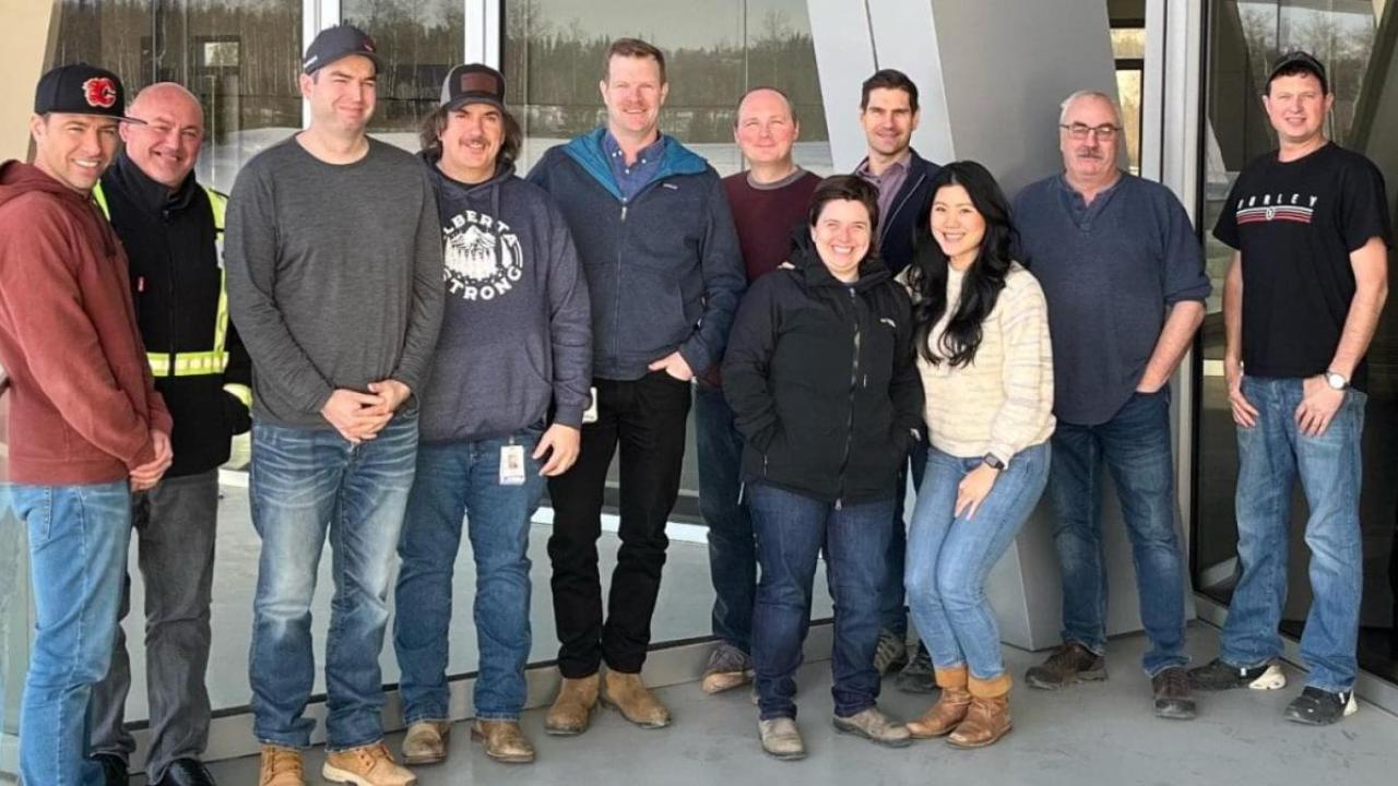A team of people in a group pose outside a building.