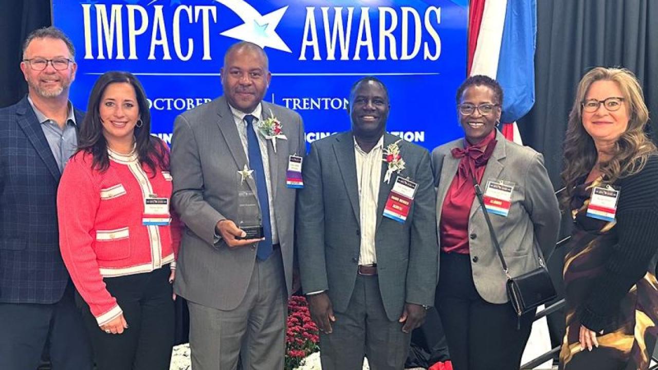Six people posing with an award