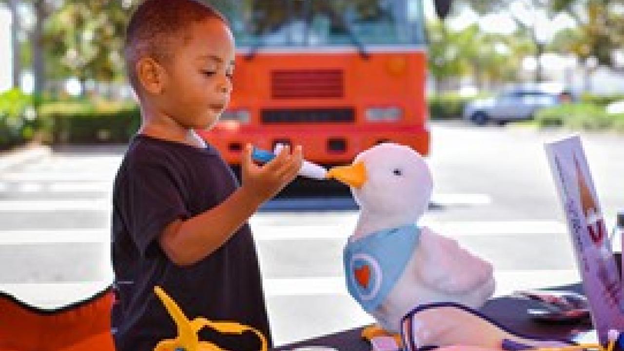 Gabe using a toy syringe to feed his Aflac stuffed duck