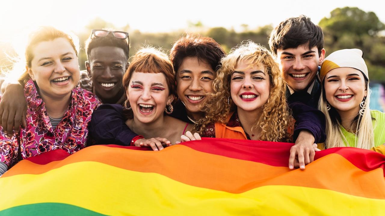 Group of individuals holding a rainbow flag.
